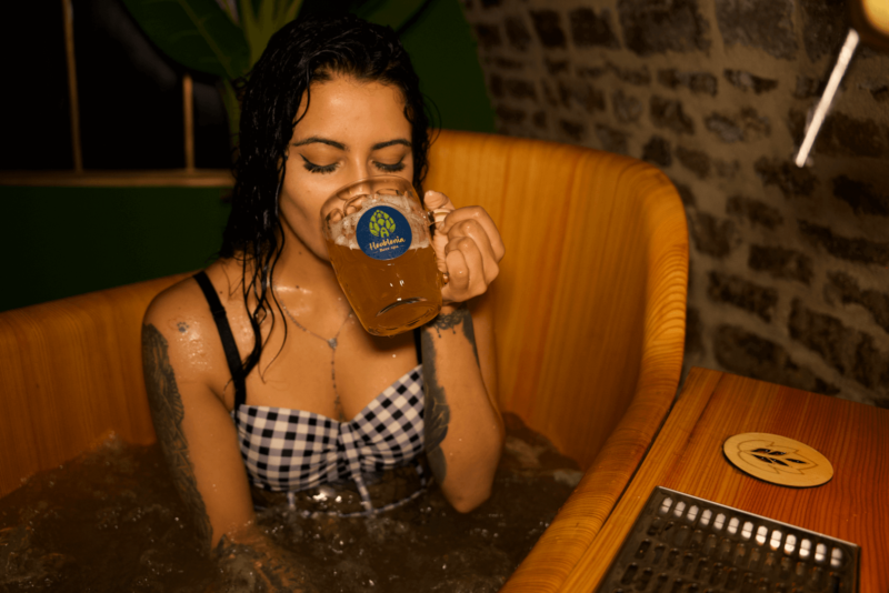 Femme dégustant une bière dans le bain en bois du spa bière Houblonia à Langres